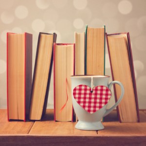 Cup with heart-shaped tea bag in front of books