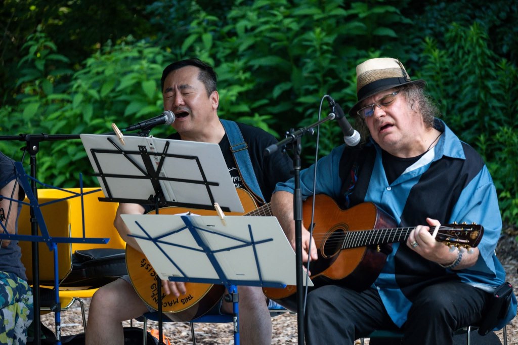 Jae Kim and Scott Cashman singing with the Back Porch Revue at the Spring Valley Nature Center, June 2025